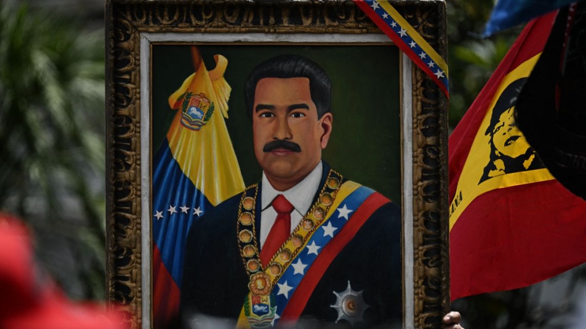 A supporter lifts up a painting of President Nicolás Maduro during military exercises announced by Maduro in Caracas on January 23, 2025.