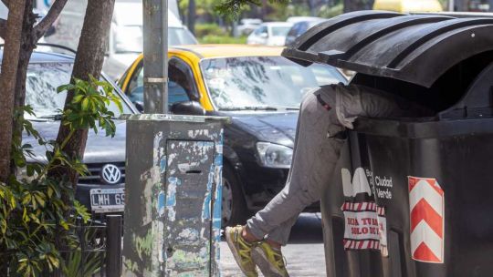 Un hombre revisa la basura, postal de la situación social.