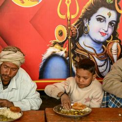 Peregrinos hindúes comen en una cocina comunitaria durante el festival Maha Kumbh Mela en Prayagraj. | Foto:R. Satish Babu / AFP
