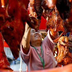 Un vendedor cuelga un cerdo asado para venderlo en un mercado en preparación para las celebraciones del Año Nuevo Lunar en Phnom Penh, Camboya. | Foto:TANG CHHIN SOTHY / AFP