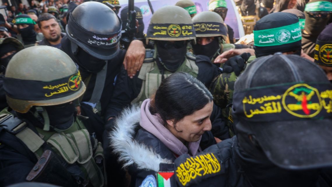 Palestinian militant group Islamic Jihad and Hamas fighters escort Israeli hostage Arbel Yehud (C) to hand her over to a Red Cross team in Khan Yunis on January 30, 2025, as part of their third hostage-prisoner exchange.