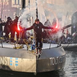 El capitán francés Jean Le Cam sostiene bengalas de humo a bordo de su monocasco Imoca 'Tout Commence en Finistere-Armor Lux' mientras navega por el canal después de ubicarse en el puesto 20 en la décima edición de la Vendée Globe alrededor del mundo en solitario en monocasco en Les Sables-d'Olonne, oeste de Francia. | Foto:Sebastien Salom-Gomis / AFP