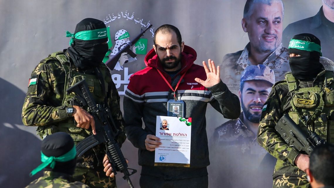 Palestinian militant group Hamas fighters escort Israeli hostage Yarden Bibas on a stage before handing him over to a Red Cross team in Khan Yunis on February 1, 2025, as part of fourth hostage-prisoner exchange. 