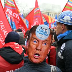 Un trabajador siderúrgico, que lleva una máscara recortada que representa al presidente estadounidense Donald Trump, participa en una manifestación mientras los sindicatos denuncian las políticas de austeridad de las instituciones y los gobiernos europeos y los recortes presupuestarios en los servicios públicos en Bruselas, Bélgica. | Foto:NICOLAS TUCAT / AFP