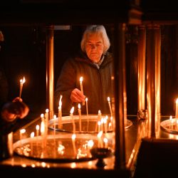 Los creyentes encienden velas en una plataforma en forma de cruz cubierta con velas unidas a frascos de miel durante una ceremonia que conmemora el día de San Haralampi, santo patrón ortodoxo de los apicultores, en la Iglesia de la Santísima Virgen en Blagoevgrad, este de Bulgaria. | Foto:NIKOLAY DOYCHINOV / AFP