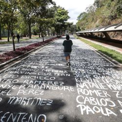 Un estudiante de la Universidad Central de Venezuela camina sobre los nombres de los estudiantes desaparecidos pintados en el piso de la entrada de la universidad en celebración del Día de la Juventud Venezolana en Caracas. | Foto:PEDRO MATTEY / AFP