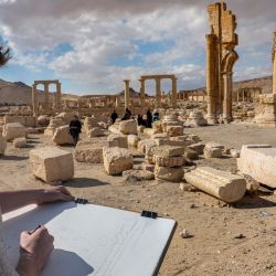 Un visitante dibuja sentado ante la Gran Columnata en las antiguas ruinas de Palmira, en el centro de Siria. Palmira es uno de los seis sitios sirios incluidos en la lista de patrimonio mundial de la UNESCO y todos ellos sufrieron algún nivel de daño durante los 13 años de guerra civil. | Foto:OMAR HAJ KADOUR / AFP