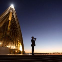 Esta fotografía tomada y publicada por la Ópera de Sídney muestra a un corneta solitario tocando The Last Post en las escaleras de la Ópera de Sídney. | Foto:DANIEL BOUD / Ópera de Sídney / AFP