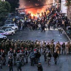 El fuego de neumáticos quemados arde mientras partidarios del movimiento islamista chiita libanés Hezbolá se presentan ante soldados del ejército libanés durante una manifestación organizada por Hezbolá para bloquear la carretera al Aeropuerto Internacional de Beirut por la decisión de prohibir el aterrizaje de dos vuelos iraníes allí, en Beirut. | Foto:Ibrahim Amro / AFP