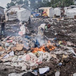Una mujer desplazada, una de las últimas en abandonar el campamento de desplazados internos de Bulengo tras ser incendiado, quema tablones de madera en la zona donde antes se construían refugios en Bulengo. | Foto:Jospin Mwisha / AFP