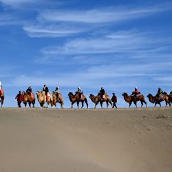 Imagen de visitantes montando camellos en la montaña Mingsha y el punto escénico de la primavera creciente, en Dunhuang, en la provincia de Gansu, en el noroeste de China. | Foto:Xinhua/Zhang Xiaoliang