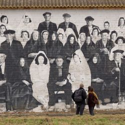 Turistas observan un mural en el pueblo de Penelles, a 40 km de Lérida, en Cataluña. Más de 100 grafitis y murales colocados en los edificios de Penelles atraen al turismo en esta zona despoblada y agrícola. El 'proyecto Gargar' comenzó en 2016 con un festival que reunía a artistas de street art de España y el extranjero. | Foto:Josep Lago / AFP