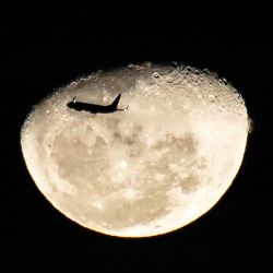 Un avión sobrevuela la Luna Gibosa Menguante vista desde Manila, Filipinas. | Foto:TED ALJIBE / AFP