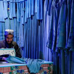 Un sastre afgano cose burkas para mujeres en una tienda de Herat. | Foto:Mohsen Karimi / AFP