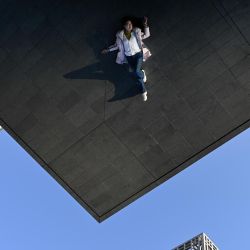 Una mujer se refleja en la pared exterior de un edificio mientras posa para una fotografía en Beijing. | Foto:Wang Zhao / AFP
