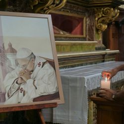 El sacerdote Martin Bourdieu enciende una vela junto a un cuadro del Papa Francisco en la Basílica San José de Flores antes de una misa para orar por su salud en Buenos Aires. | Foto:JUAN MABROMATA / AFP