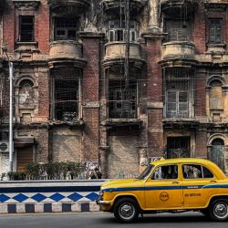 Esta fotografía muestra al conductor de un taxi amarillo Hindustan Ambassador pasando por delante de un edificio histórico en Calcuta, India. | Foto:DIBYANGSHU SARKAR / AFP