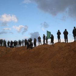 Los combatientes del grupo militante palestino Hamás se mantienen firmes antes de la entrega de los cuerpos de cuatro rehenes israelíes en Khan Yunis, en el sur de Gaza. | Foto:Eyad Baba / AFP