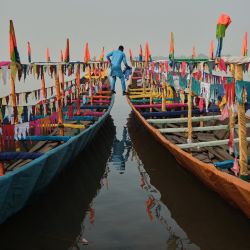 Un hombre pasa de una piragua a otra durante la regata anual de barcos en Yauri, estado de Kebbi, Nigeria. | Foto:TOYIN ADEDOKUN / AFP
