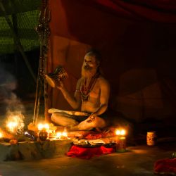 Un sadhu, o santo hindú, que llegó del festival Kumbh Mela en Prayagraj, toca los tambores mientras está sentado dentro de su tienda, a orillas del río Ganges en Chauki ghat en Varanasi. | Foto:NIHARIKA KULKARNI / AFP