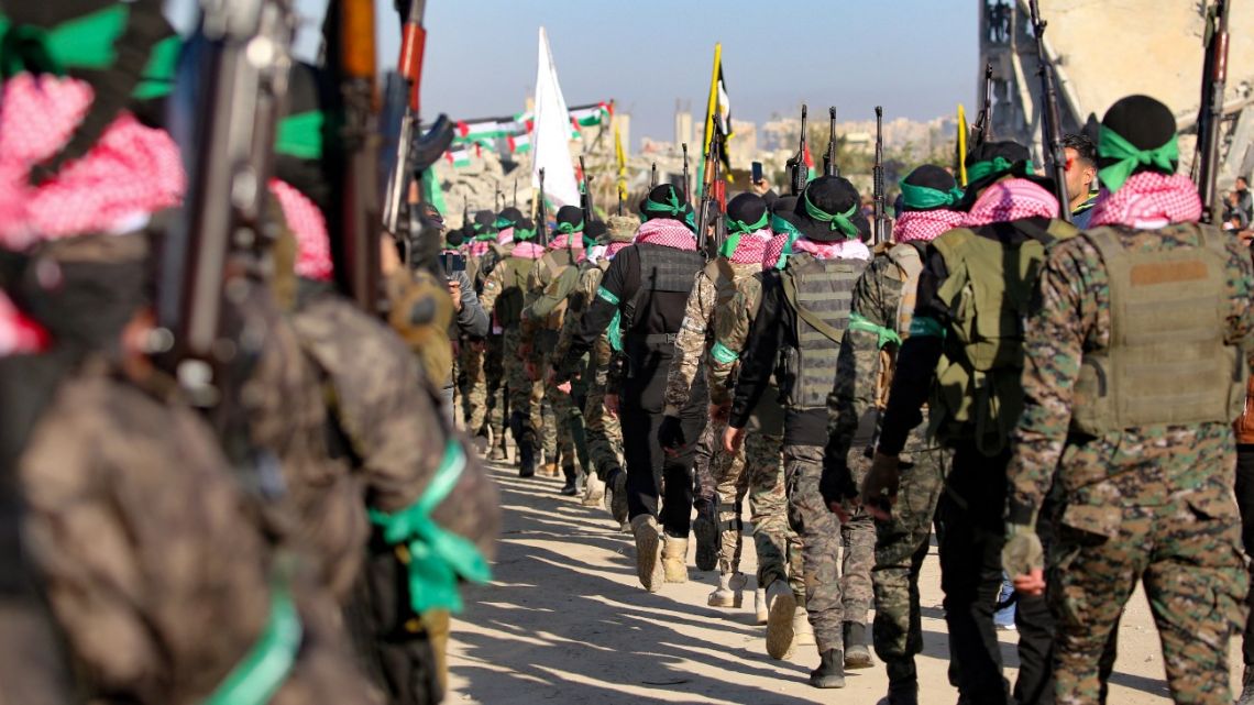 Palestinian Hamas fighters, parade before handing over Israeli hostages to a Red Cross team in Khan Yunis in the southern Gaza Strip on February 15, 2025,