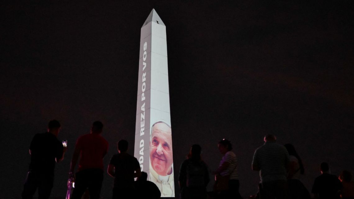 People look at the obelisk illuminated with the image of Pope Francis in Buenos Aires on February 24, 2025. 