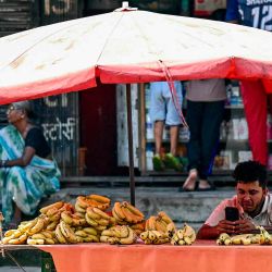  Un vendedor de plátanos mira su teléfono móvil mientras espera a los clientes en una calle de Mumbai. Foto de Indranil MUKHERJEE / AFP | Foto:AFP