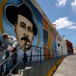  Un hombre pasa junto a un mural que representa al médico venezolano José Gregorio Hernández en una calle del barrio La Pastora en Caracas. Foto de Pedro MATTEY / AFP | Foto:AFP