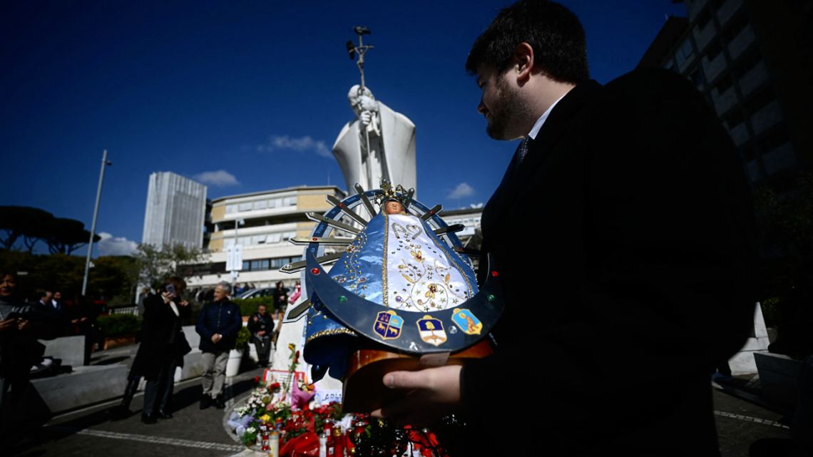 Faithful from Argentina gather to pray with a statue of Our Lady of Luján in front of the statue of John Paul II outside the Gemelli University Hospital where Pope Francis is hospitalized with pneumonia, in Rome on March 04, 2025. Pope Francis "slept all night long" the Vatican said on March 4, 2025 after he suffered two breathing attacks on Monday, as the 88-year-old pontiff struggles to recover from pneumonia. 