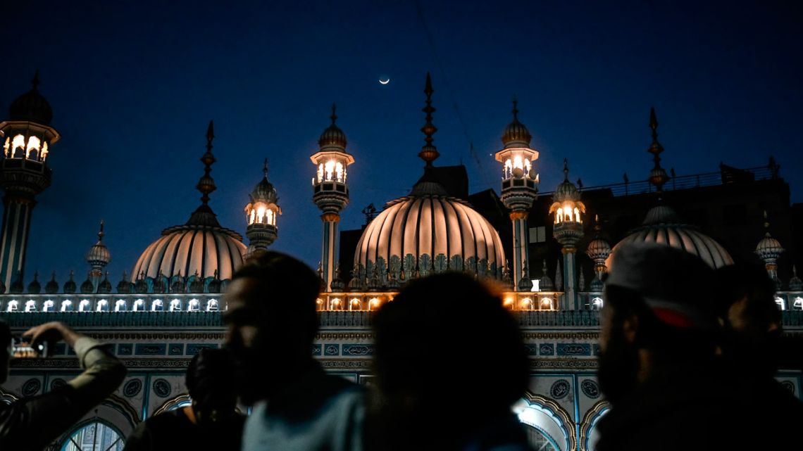 The moon rises above a mosque as Muslims leave after offering prayers on the first day of the Islamic holy fasting month of Ramadan in Rawalpindi on March 2, 2025. 