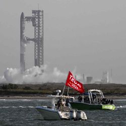 La gente se sienta en un barco con una bandera de Trump mientras observa el despegue de la nave Starship de SpaceX desde Starbase cerca de Boca Chica, Texas.  | Foto:AFP