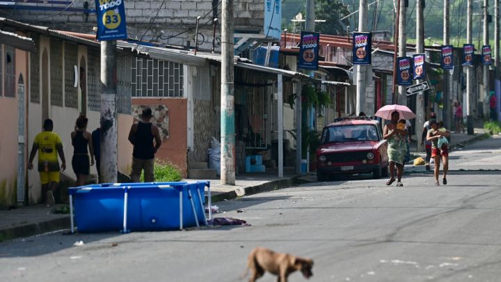 People walk in the street in the neighbourhood where at least 22 people were killed on the eve in Guayaquil, Ecuador, on March 7, 2025.