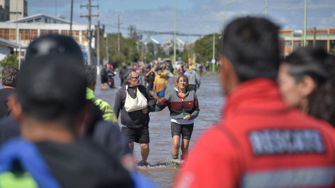 People walk through flooded waters the day after a heavy storm in Bahía Blanca, 600 km south of Buenos Aires on March 8, 2025. 