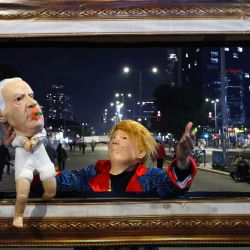 Un manifestante anima una instalación con marionetas que representan al presidente estadounidense Donald Trump y al primer ministro israelí Benjamin Netanyahu durante una manifestación de familiares y amigos de israelíes tomados como rehenes por militantes palestinos en Gaza desde octubre de 2023, para exigir acciones para su liberación, frente al Ministerio de Defensa israelí en Tel Aviv. | Foto:JACK GUEZ / AFP