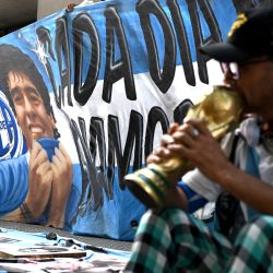 Una pancarta con la imagen de Diego Maradona se ve mientras un fanático espera afuera del tribunal de San Isidro durante el juicio por la muerte de la leyenda del fútbol argentino en San Isidro, provincia de Buenos Aires, Argentina. | Foto:LUIS ROBAYO / AFP