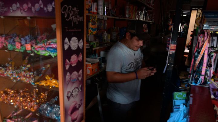 A kiosk worker uses his mobile phone during a power outage in Buenos Aires on March 5, 2025.