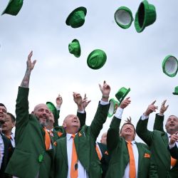 Los aficionados a las carreras, vestidos con los colores irlandeses, lanzan sus sombreros al aire mientras se celebra el Día de San Patricio en el hipódromo de Cheltenham, en Cheltenham, oeste de Inglaterra. | Foto:JUSTIN TALLIS / AFP