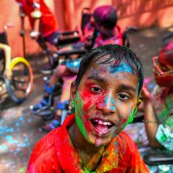 Un niño con necesidades especiales reacciona tras ser manchado con colores durante las celebraciones de Holi, el festival hindú de los colores de primavera, en una escuela para niños con necesidades especiales (CwSN), en Mumbai, India. | Foto:Indranil Mukherjee / AFP