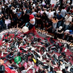 Personas colocan pares de zapatos durante la vigilia "Luto Nacional Tehuchitlán" en memoria de quienes perdieron la vida en el Rancho Izaguirre en Guadalajara, Jalisco, México. El macabro hallazgo de huesos, zapatos y ropa carbonizados en el Rancho Izaguirre, presunto campo de entrenamiento de un cártel de la droga, ha generado demandas de respuestas y justicia por parte de los familiares de las más de 100,000 personas desaparecidas en México. | Foto:ULISES RUIZ / AFP