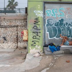 Un hombre descansa en una playa, mientras una mujer juega al fronton en el suburbio de Palaio Faliro, en la costa del Golfo Sarónico, al sur de Atenas, Grecia. | Foto:Angelos Tzortzinis / AFP