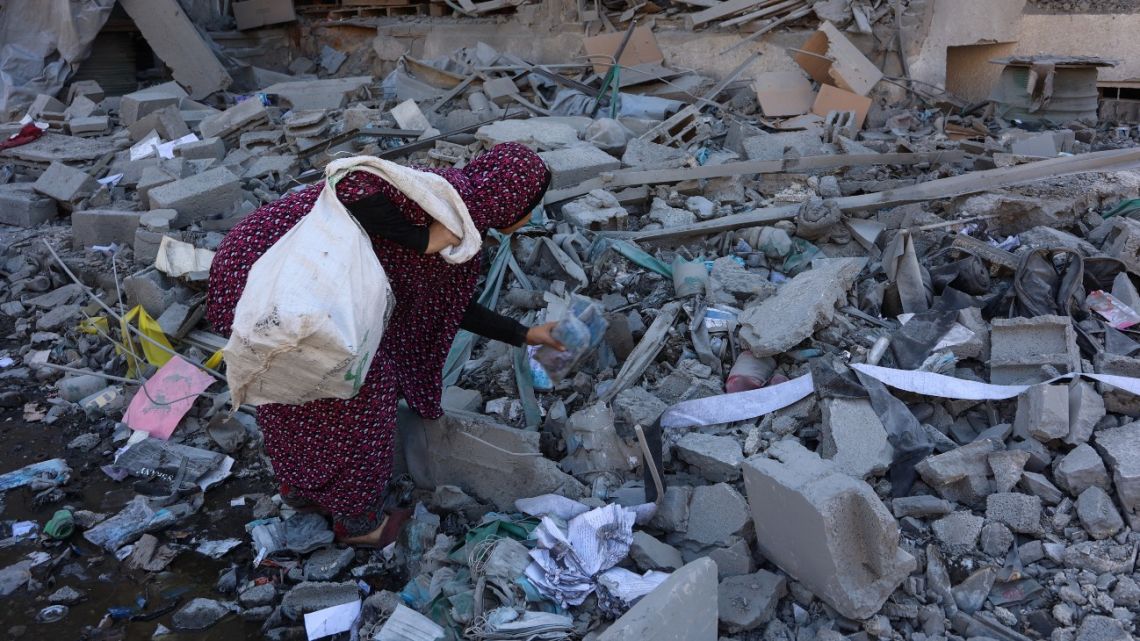 A Palestinian woman inspects the rubble of the Elias Tarazi family house, after it was destroyed in an Israeli strike in al-Sabra neighbourhood in Gaza City on March 19, 2025.