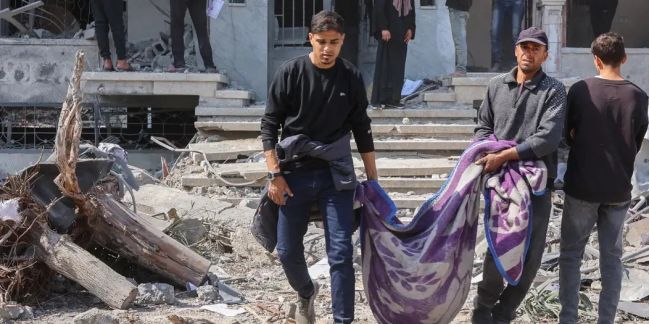 Residentes palestinos cargan un cuerpo sacado de los escombros tras los nuevos ataques israelíes, en el este de la ciudad de Gaza, este 18 de marzo de 2025.