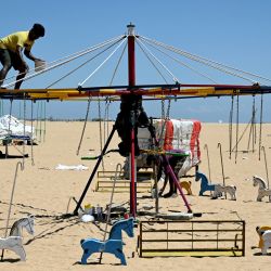 Trabajadores pintan un tiovivo durante una tarde calurosa en la playa Marina de Chennai, India. | Foto:R. Satish Babu / AFP