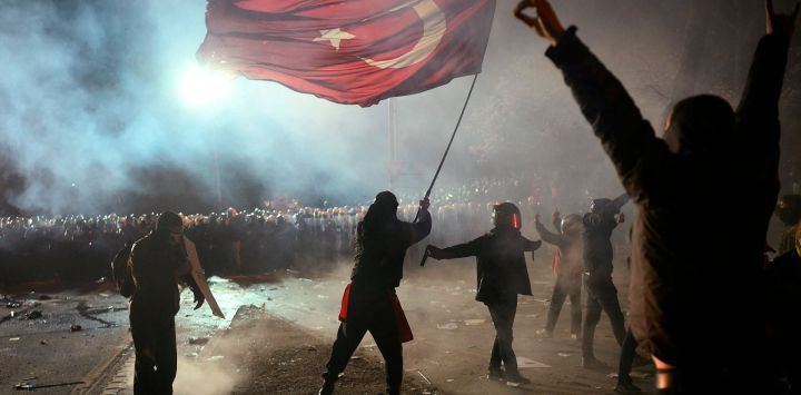 Un manifestante ondea una bandera turca frente a la policía antidisturbios durante una manifestación en apoyo al alcalde de Estambul. Foto de Angelos Tzortzinis / AFP