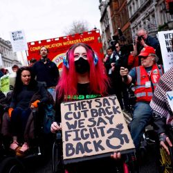 Manifestantes en silla de ruedas sostienen pancartas con la leyenda "Ellos dicen recortes, nosotros decimos lucha" y "Bienestar, no guerra" en Londres. Foto de BENJAMIN CREMEL / AFP | Foto:AFP