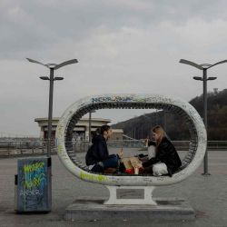 Unas niñas almuerzan sentadas en un banco inusual en el barrio de Podil, en Kiev. Foto de Tetiana DZHAFAROVA / AFP | Foto:AFP