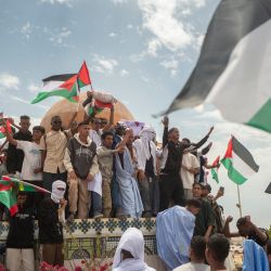 Un grupo de personas ondea banderas palestinas sobre la réplica de la mezquita Al-Aqsa en la rotonda de Jerusalén, durante una manifestación pro palestina cerca de la embajada de Estados Unidos en Nuakchot, Mauritania. | Foto:MICHELE CATTANI / AFP