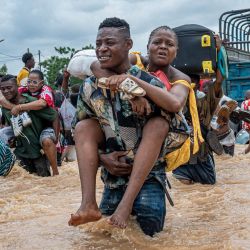 Un residente carga a una mujer mientras otros cruzan las aguas inundadas en el distrito de Ndjili, Kinshasa. Las fuertes lluvias en Kinshasa, la capital de la República Democrática del Congo, han dejado alrededor de 30 muertos y han causado estragos en la megaciudad centroafricana. | Foto:Hardy Bope / AFP
