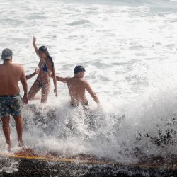 Personas son bañadas por las olas producidas por un oleaje anómalo, en la playa San Bartolo, en Lima, Perú. | Foto:Xinhua/Mariana Bazo