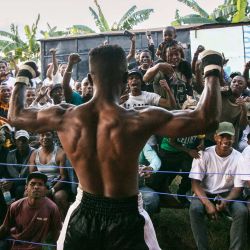 Un luchador, felicitado por el público tras ganar su combate, recoge dinero en un sombrero durante el evento deportivo "Morengy Iarivo", una competición de morengy celebrada por primera vez en Antananarivo. | Foto:RIJASOLO / AFP